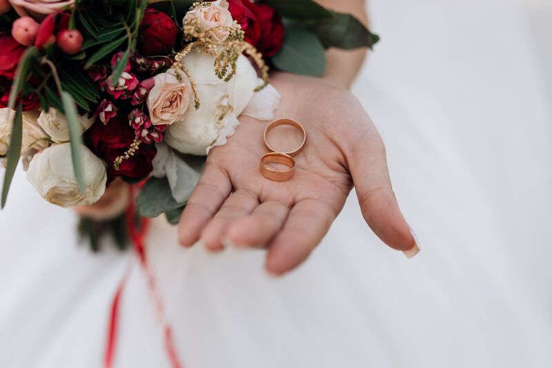 Wedding rings with bouquet of red and white flowers